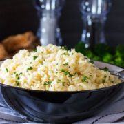 A bowl of rice Pilaf in a dish with salt and pepper mills in the background.