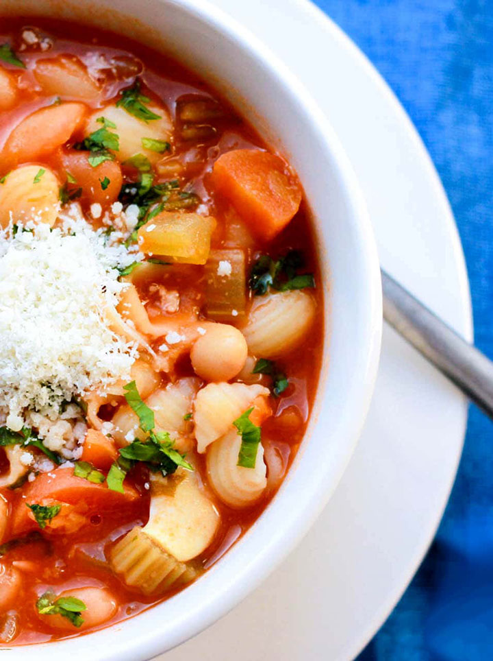 A close up, long view of a white bowl filled with the Pasta Fagioli and topped with cheese