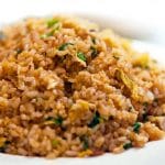 A close up of golden fried rice showing the freen onions and egg throughout