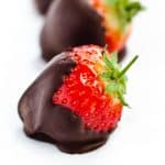 3 chocolate covered strawberries with their tops and stems exposed