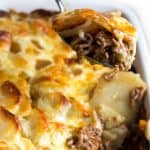 a spoon serving cottage pie stopped with cheesy potatoes