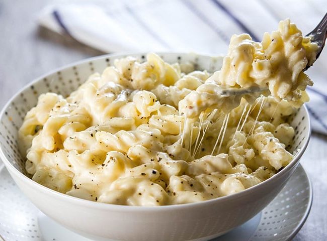 A fork digging into a big bowl of Homemade Creamy Mac and Cheese