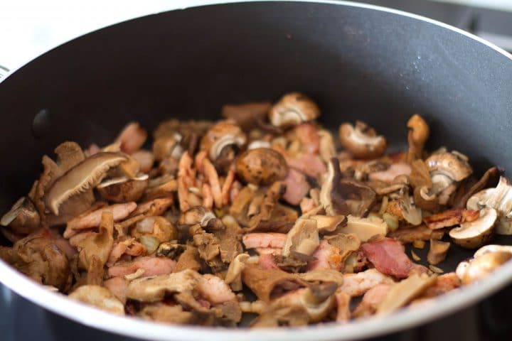 The bacon, mushrooms, onions and garlic cooking in the pan