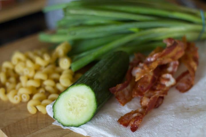 Pasta, bacon, cucumbers and green onions on a table