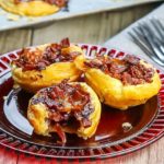 Three Cranberry Brie Tarts with Bacon & Red Onion on a red plate with more tarts in the background