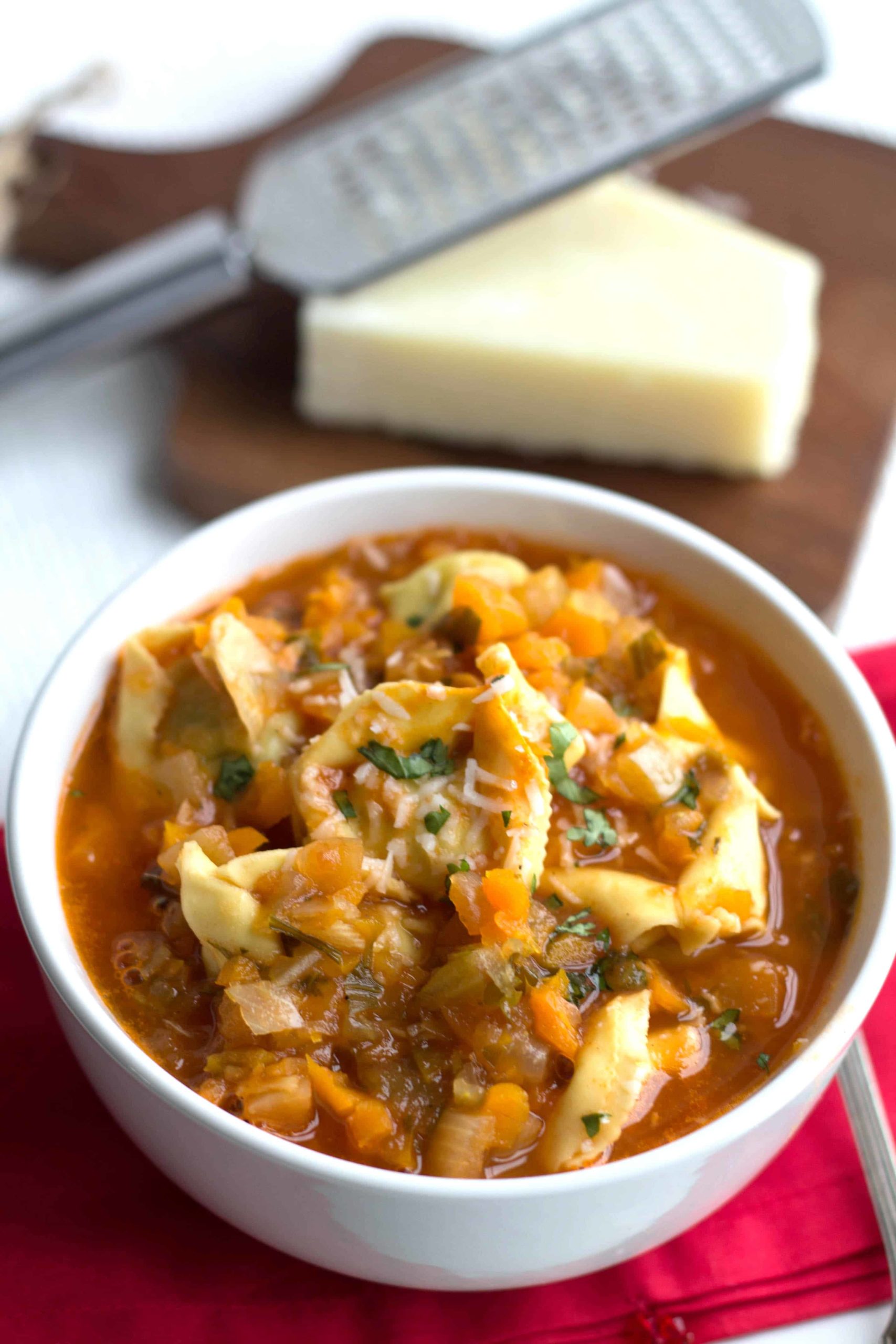 tortellini  soup in a bowl with grated parmesan