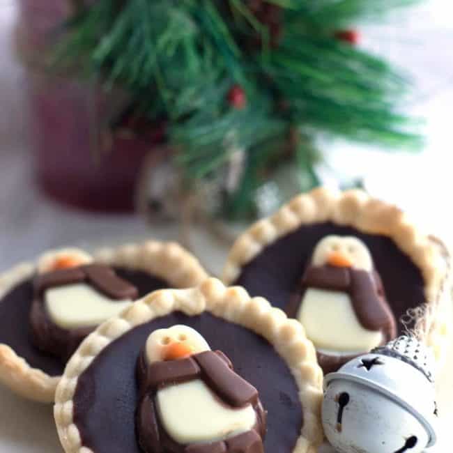 Dark Chocolate Ganache Tarts decorated with penguin chocolates on a plate