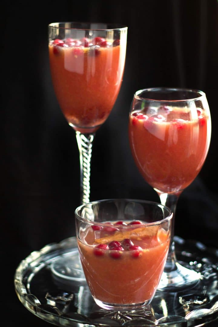 three different cocktail glasses of Spiced Cranberry & Orange Cocktail on a crystal platter