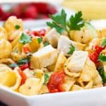 pasta salad with chicken, peppers and herbs in a white bowl