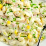 a close up image of the finished tuna pasta salad in a bowl with a spoon.