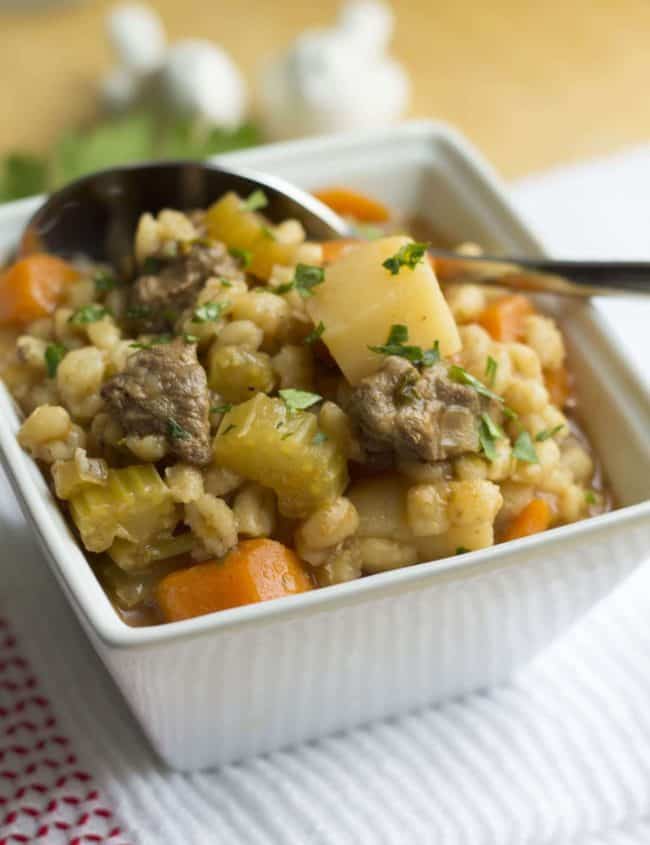 Beef and Barley Soup piled high in a bowl with a spoon in it