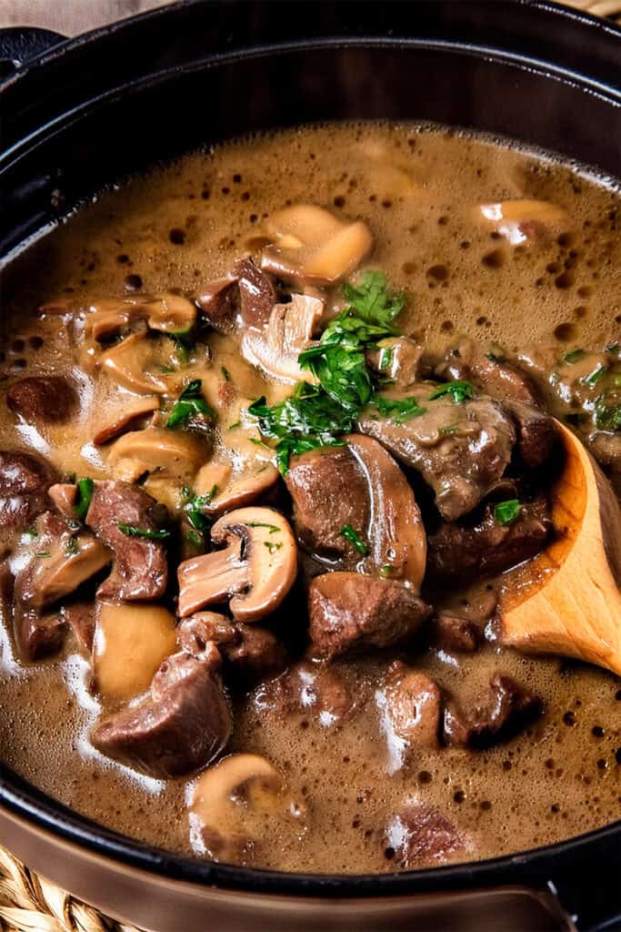 A close-up of a hearty Slow Cooker Beef with Mushrooms stew in a slow cooker. 