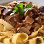 A plate of tagliatelle pasta topped with a rich and hearty slow cooker beef with mushrooms sauce.