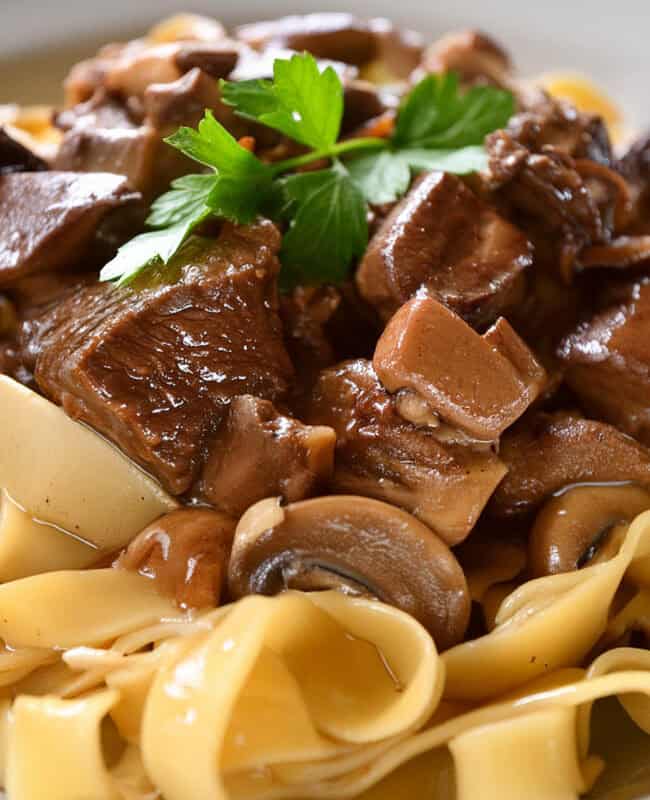 A plate of tagliatelle pasta topped with a rich and hearty slow cooker beef with mushrooms sauce.