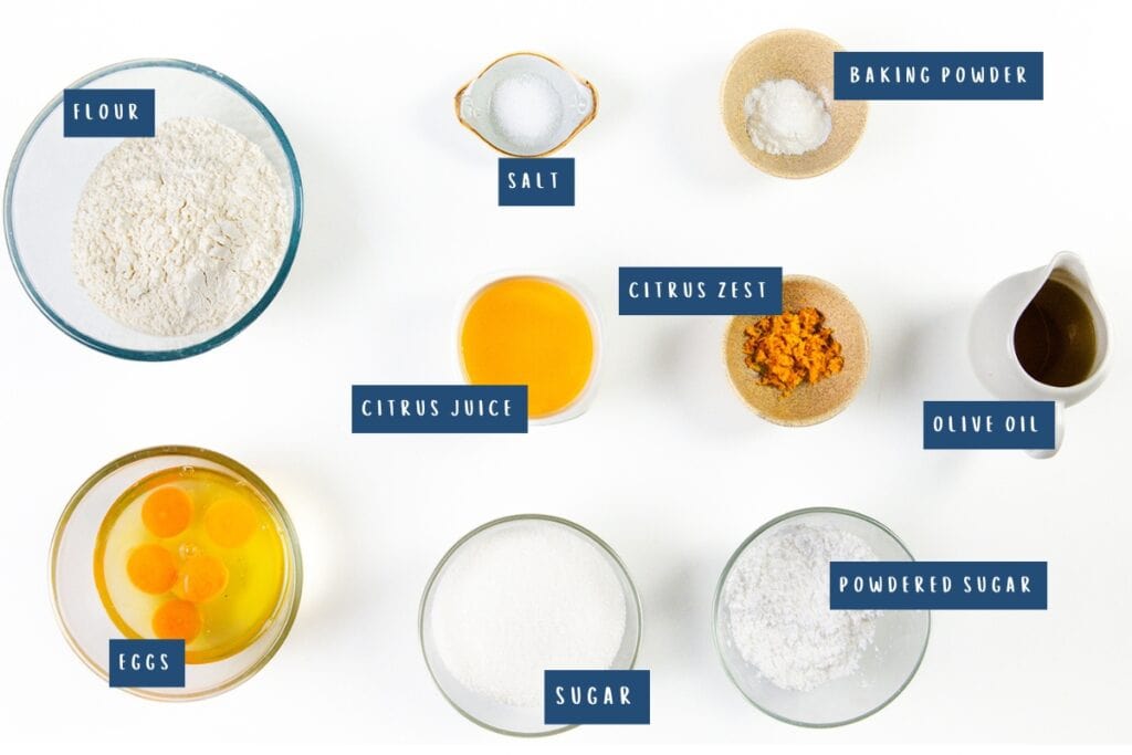 A top-view of baking ingredients for a Citrus and Olive Oil Bundt Cake, labeled: flour, eggs, sugar, salt, citrus juice, citrus zest, baking powder, olive oil, and powdered sugar, all neatly arranged in bowls on a pristine white background.