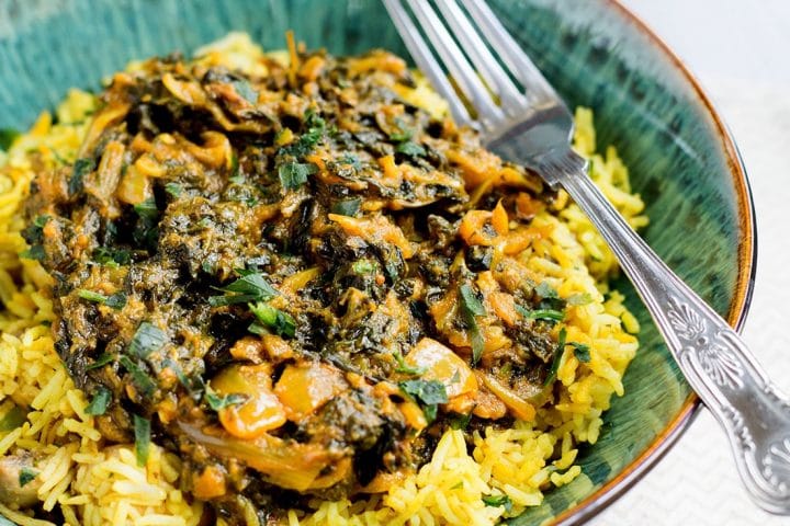 A close up of a portion of spinach curry Sag Bahji served on vibrant yellow rice