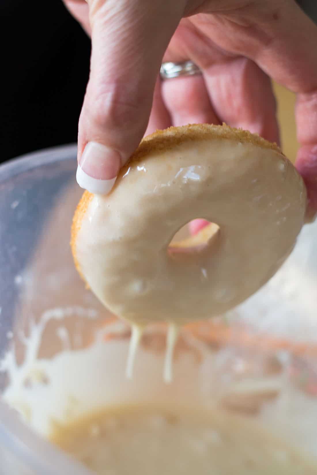 A doughnut being dipped in icing 