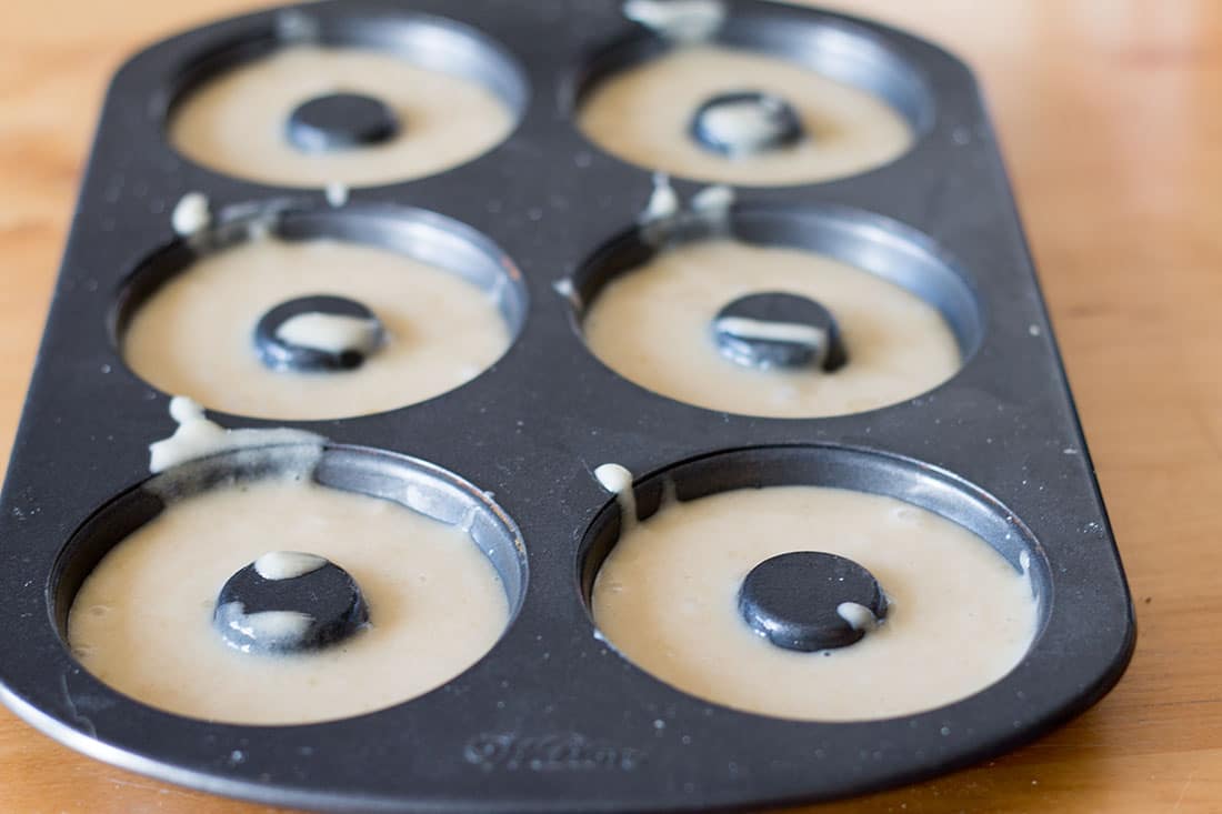 A doughnut pan with batter filling the doughnut sections 3/4 of the way full