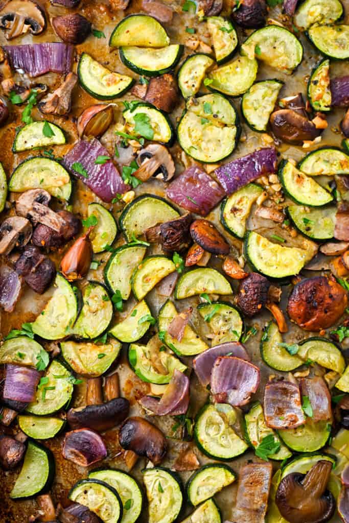 a close up image of the roasted vegetables in a sheet pan.