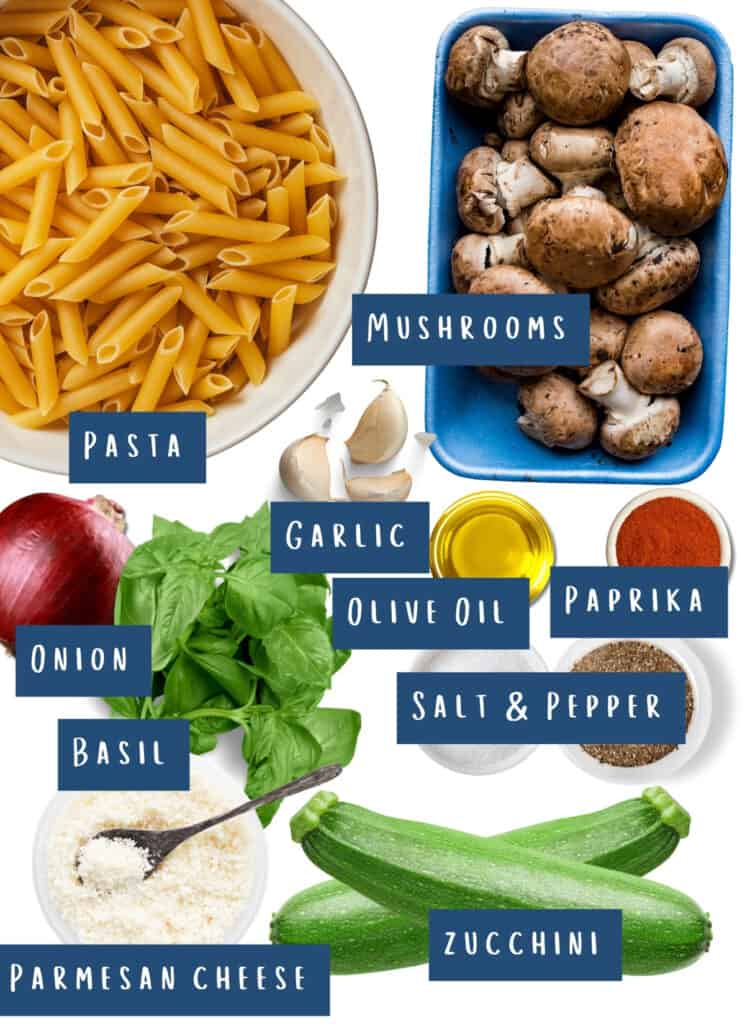 An assortment of fresh ingredients labeled for cooking Roasted Vegetable Pasta, including pasta, mushrooms, a red onion, garlic cloves, olive oil, paprika, salt and pepper, fresh basil, grated Parmesan cheese, and two zucchini.