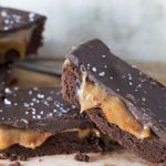 Cut slices of the Salted Chocolate & Caramel Bars stacked and piled on each other with the caramel oozing out and the salt on top