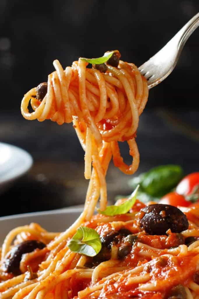 Spaghetti Alla Puttanesca twirled on a fork over the plate