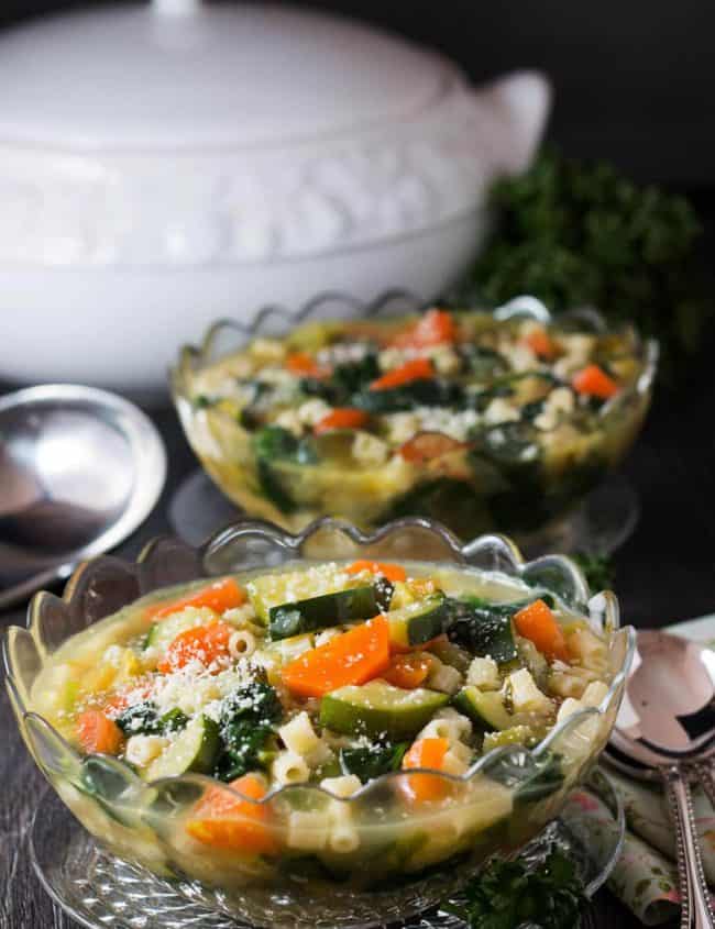 teo bowls of Spring Vegetable Soup and a serving spoon in the background