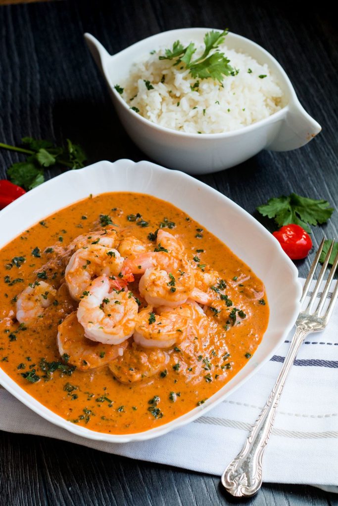 Thai red curry with a bowl of rice in the background.