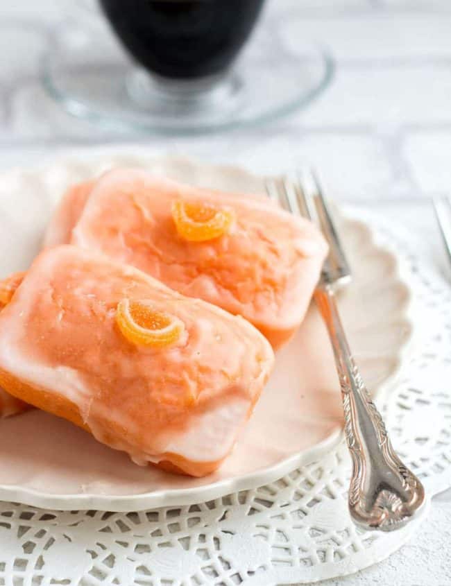 two Glazed Orange Cakeson a plate with a fork next to them