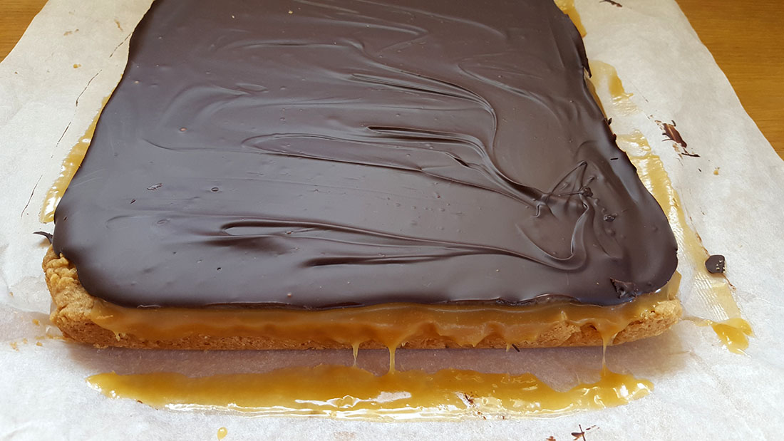 the Billionaire Shortbread removed from the pan showing each layer of shortbread, oozing caramel and the set chocolate.