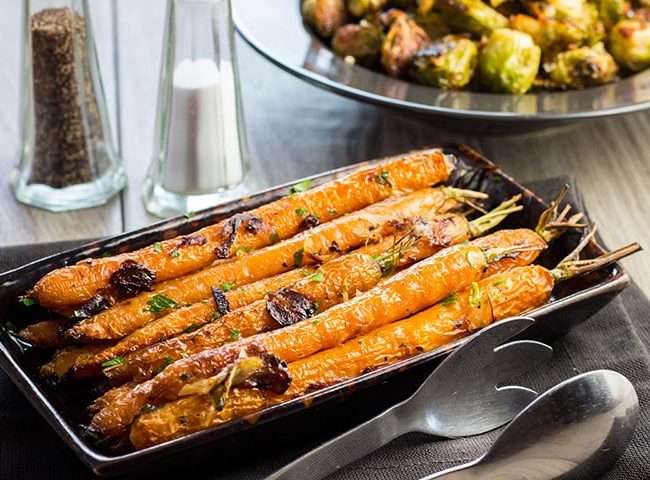 Buttery Balsamic Garlic Roasted Carrots on a serving dish sprinkled with parsley