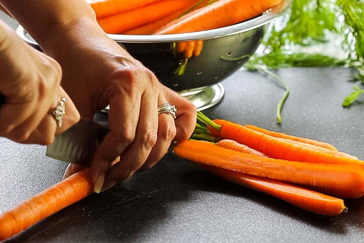 A carrot being cut in half lengthwise.