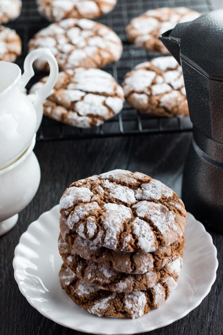 Three Spiced Ginger Crinkle Cookies on a plate with more on a cooling rack in the background