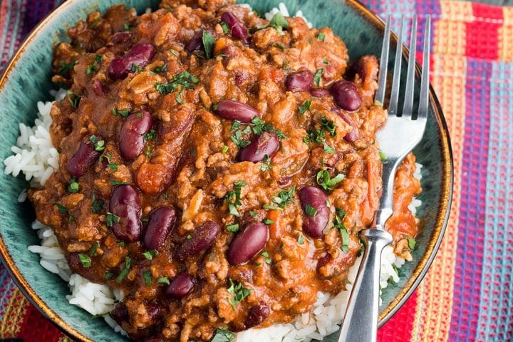 A big bowl of Classic Chilli Con Carne on a bed of rice with a fork in the bowl