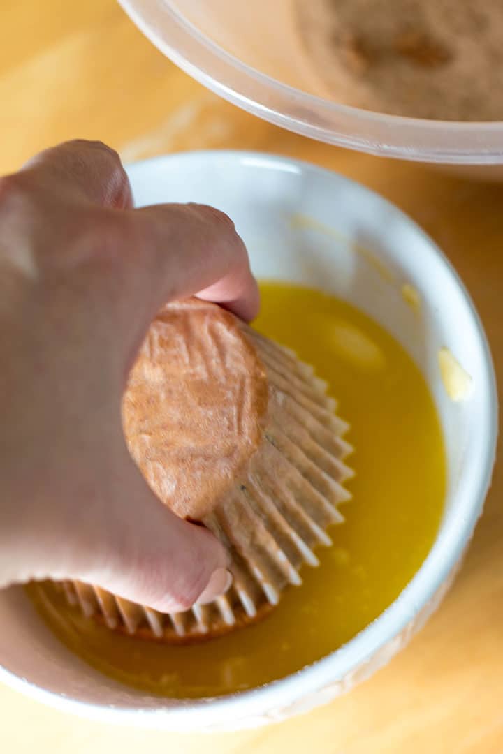 the muffin being dipped into the melted butter