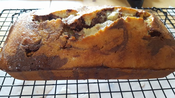 The cake on a cooling rack with the glaze freshly applied