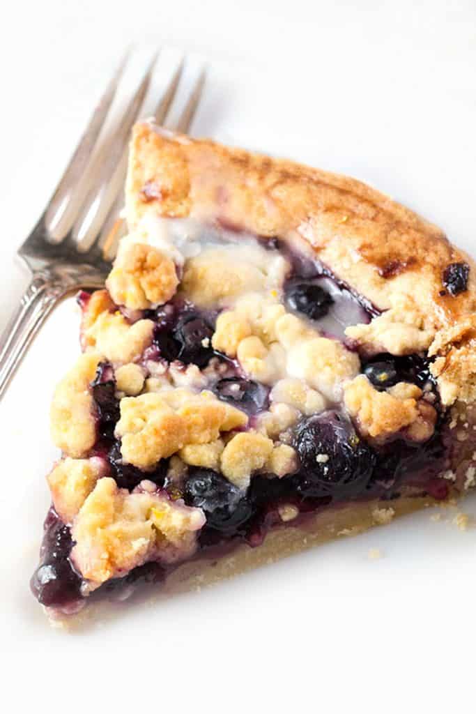 A slice of a blueberry tart with a white background