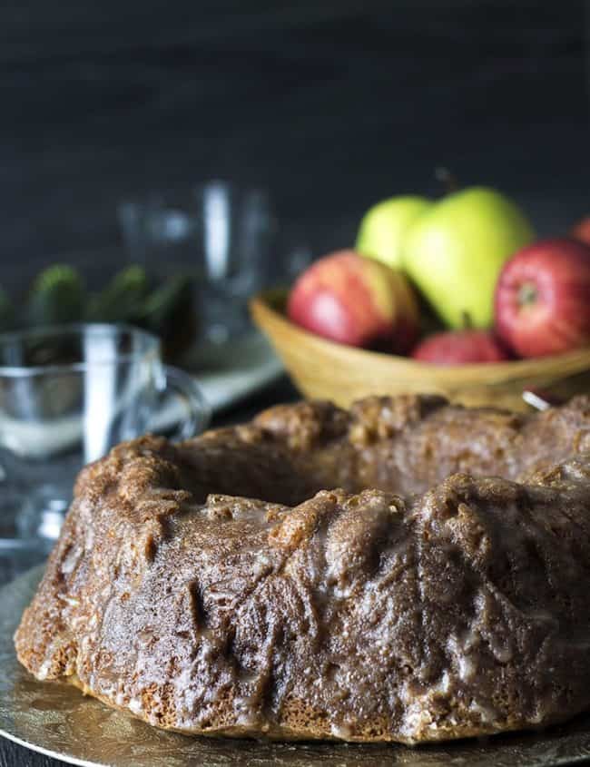 Glazed Apple Bundt Cake on a gold platter with apples in the background