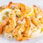 A plate full of shrimp scampi and spaghetti sprinkled with fresh chopped parsley