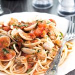 A plate full of Spaghetti with Red Clam Sauce with the clams still in their shells.