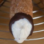 a close up of a cannoli with filling that's running out of it.