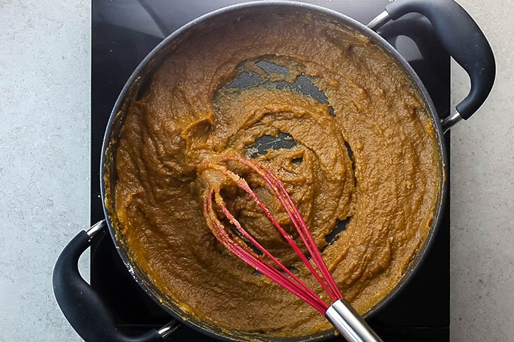 The cooked pumpkin filling in the pan with a whisk