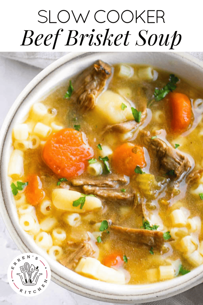 A wam bowl of slow cooker beef brisket soup with pieces of beef brisket, carrots, potatoes, celery, onion, pasta, and a beef broth. Fresh parsley sprinkled on top.