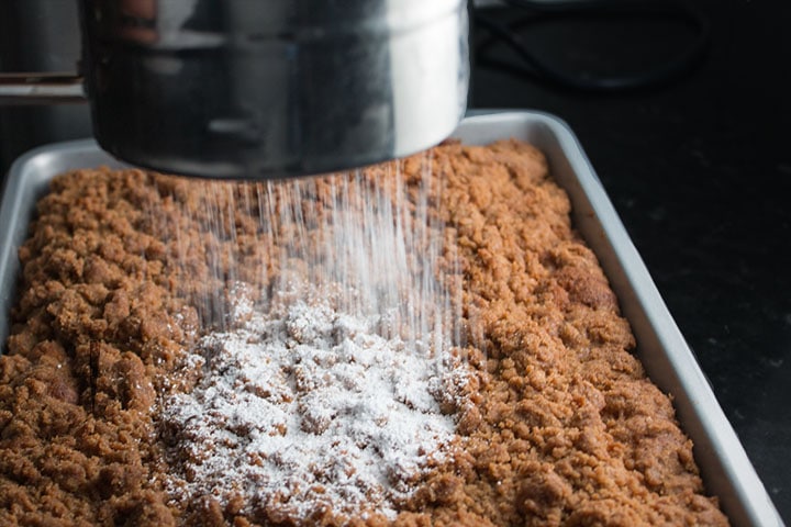 The powdered sugar being added to the cooled cake