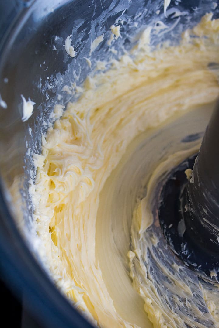 A food processor bowl with creamed butter and sugar