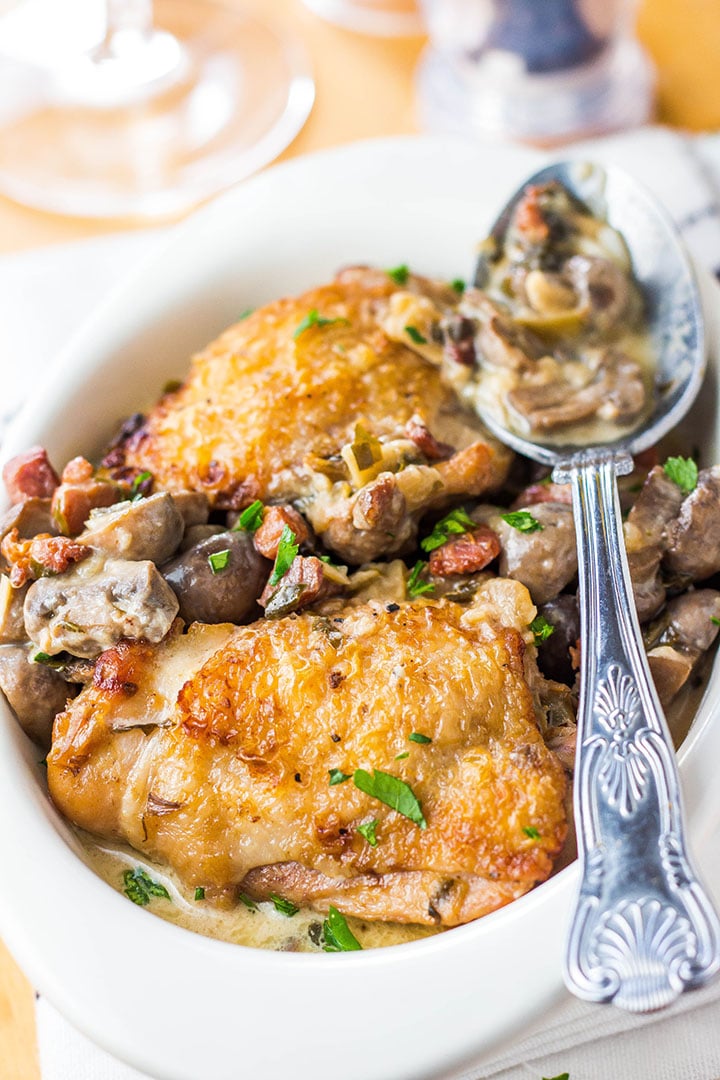 A plate of chicken bacon and mushrooms with a spoon