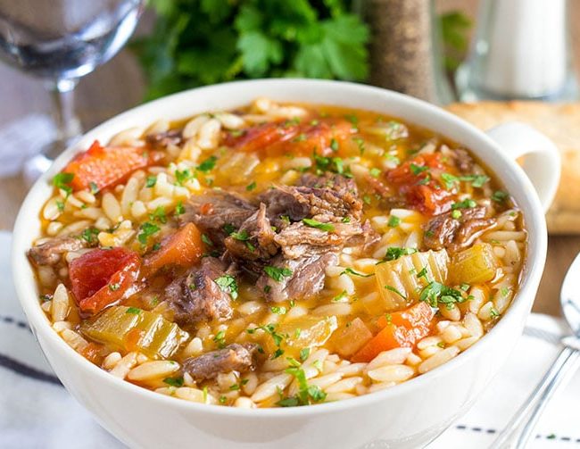 a big bowl full of Slow Cooker Oxtail Orzo Soup sprinkled with fresh parsley