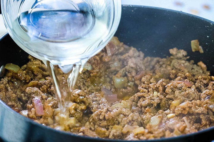 The wine being added to the beef mixture