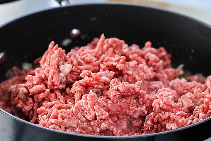 The meat added to the pan with the onion and garlic mixture