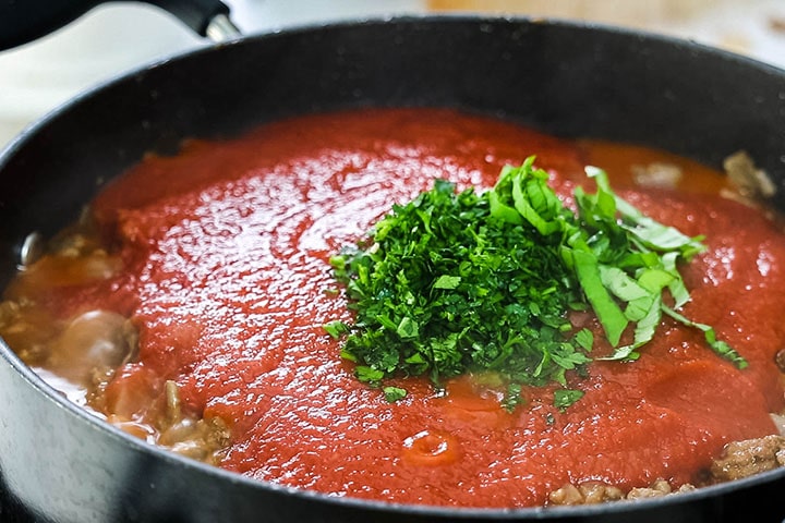 The fresh herbs and tomatoes added to the pan with the meat mixture.